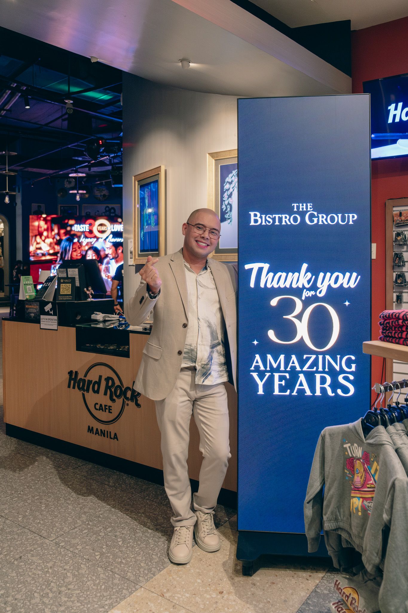 Brian Peck, Hard Rock Café director of operations, beside a lit Bistro Group sign thanking guests for 30 amazing years
