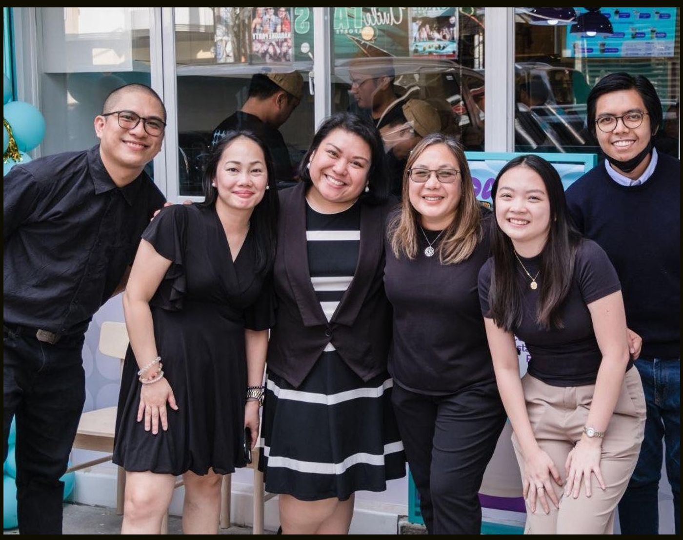 Six people in mostly black smile together at the opening of the Daily by Bo’s Coffee flagship store