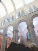 Romanesque arches and galleries inside the Santiago Cathedral, the botafumeiro swinging high above the crowd