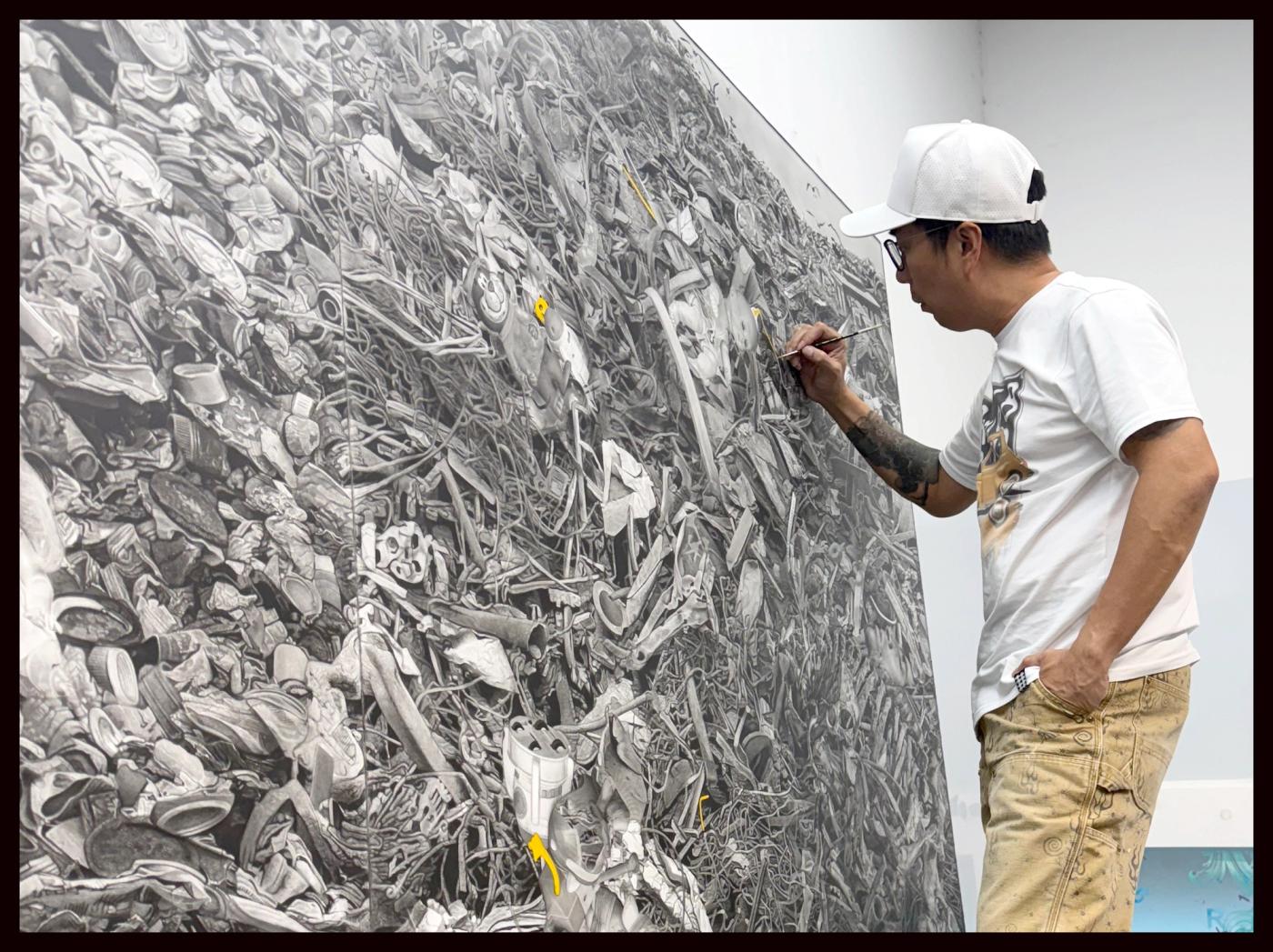 Ronald Ventura adds fine detail with a brush to a vast grayscale painting of heaped scrap and debris for his Venice Biennale show