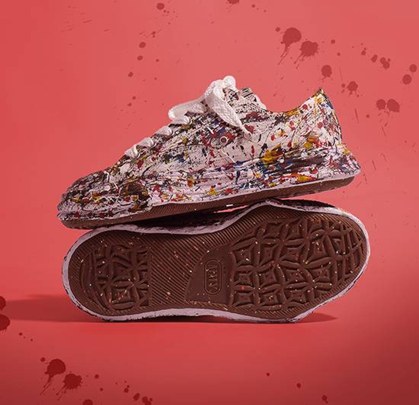 Close-up view of red Maison Mihara Yasuhiro Peterson 23 low-top canvas sneakers featuring unique hand-sculpted soles and paint-splattered details