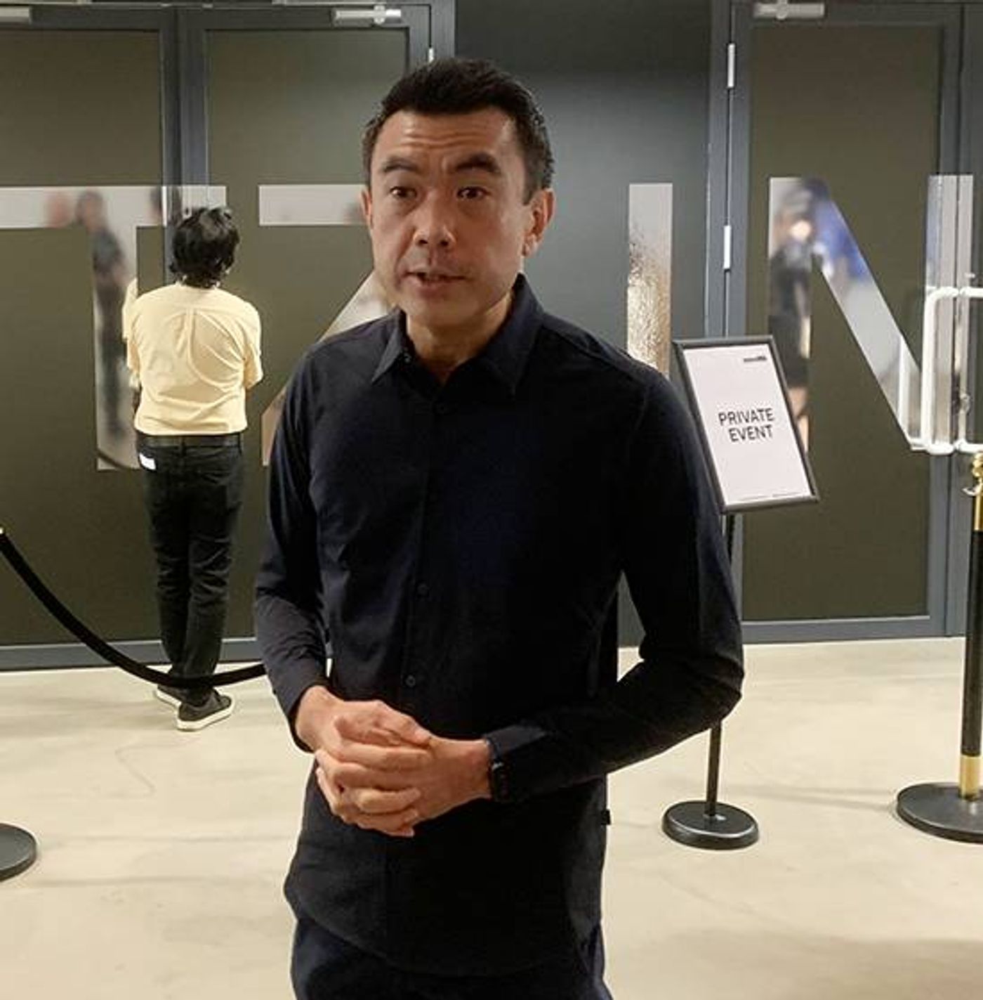 Museum director Eugene Tan in a dark shirt standing with clasped hands in a gallery lobby