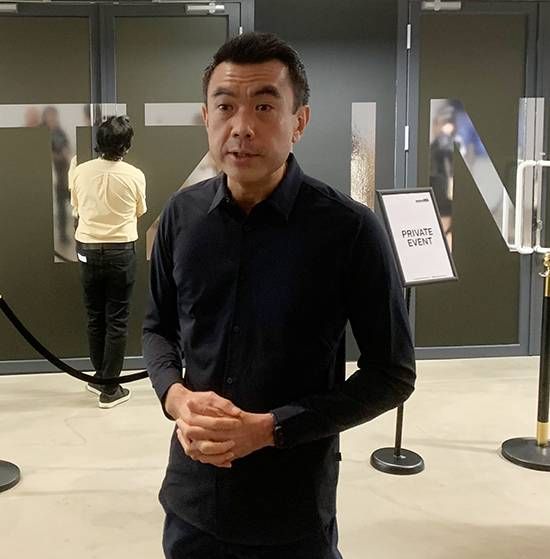 Museum director Eugene Tan in a dark shirt standing with clasped hands in a gallery lobby