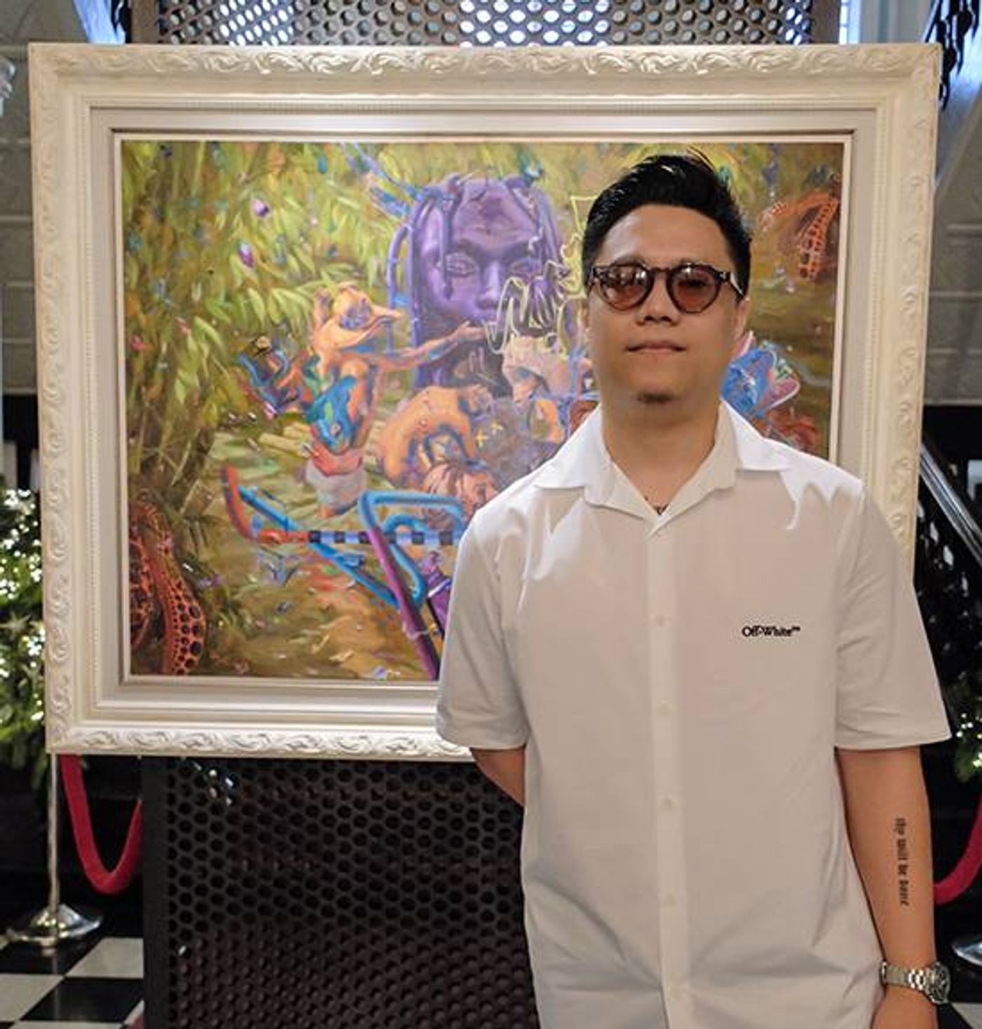 Portrait of artist Ronson Culibrina standing in front of one of his modern pop-infused landscape paintings