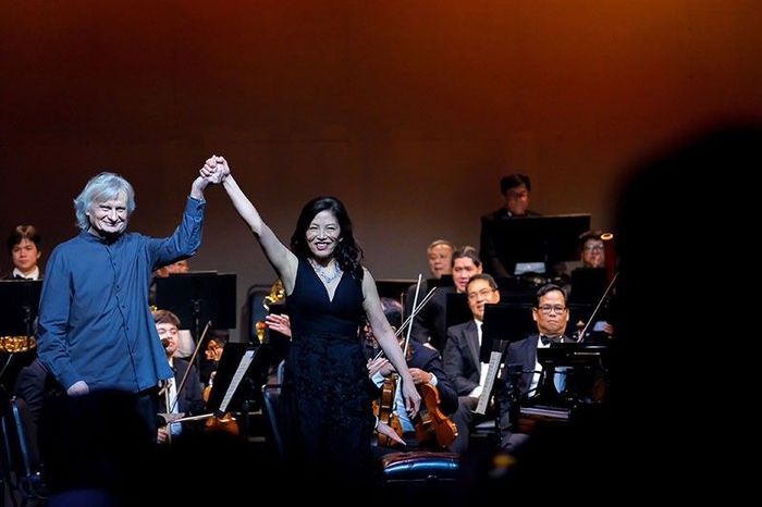 Cecile Licad, in a black gown, raises joined hands with the conductor at curtain call before the Philippine Philharmonic Orchestra