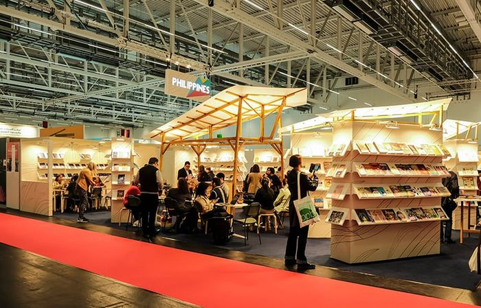 The Philippine pavilion stand at the Frankfurt Book Fair featuring custom wooden shelving units filled with books under warm spotlights