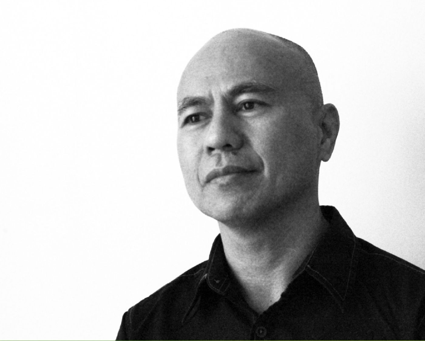 Black-and-white portrait of Arvin Flores, bald in a dark shirt against a white wall