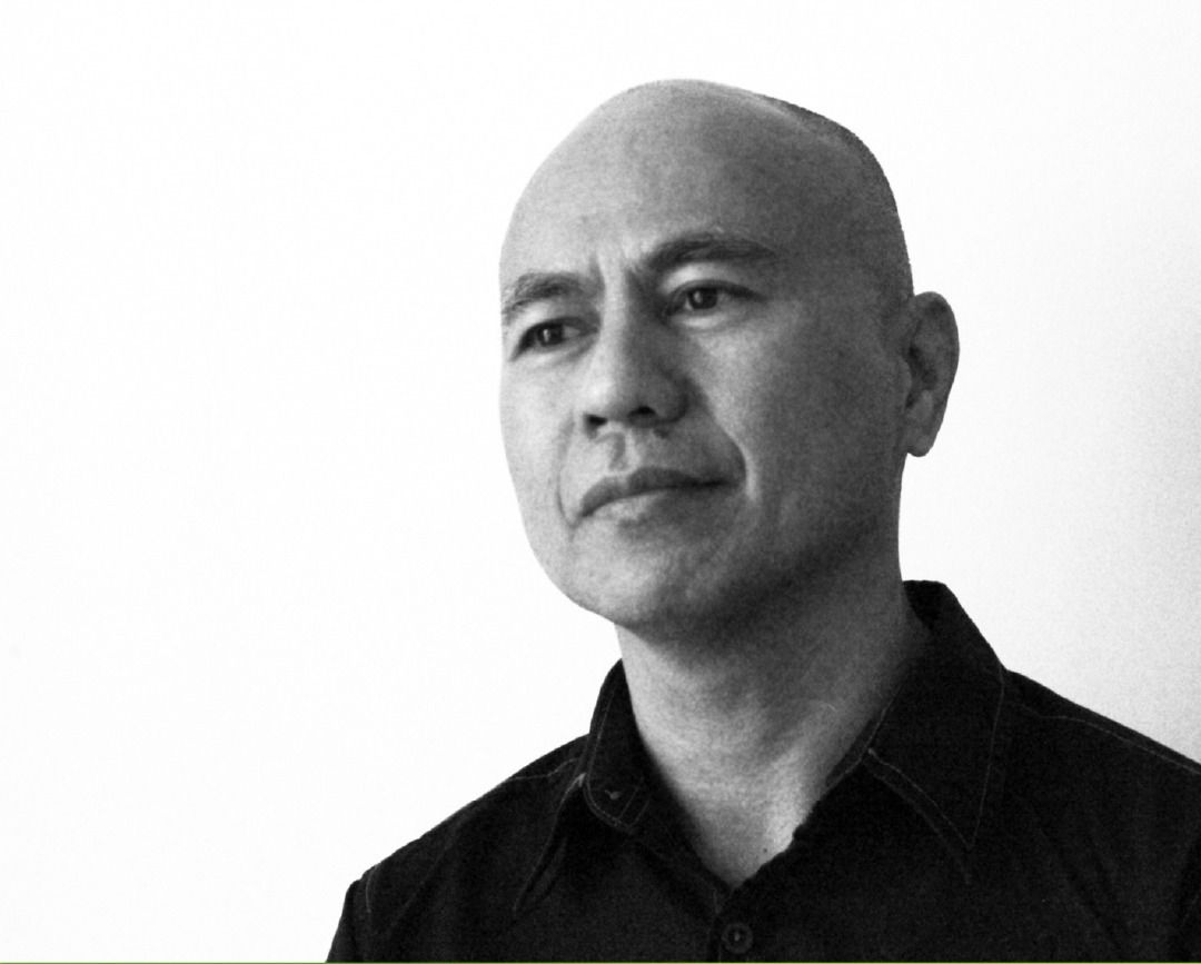 Black-and-white portrait of Arvin Flores, bald in a dark shirt against a white wall