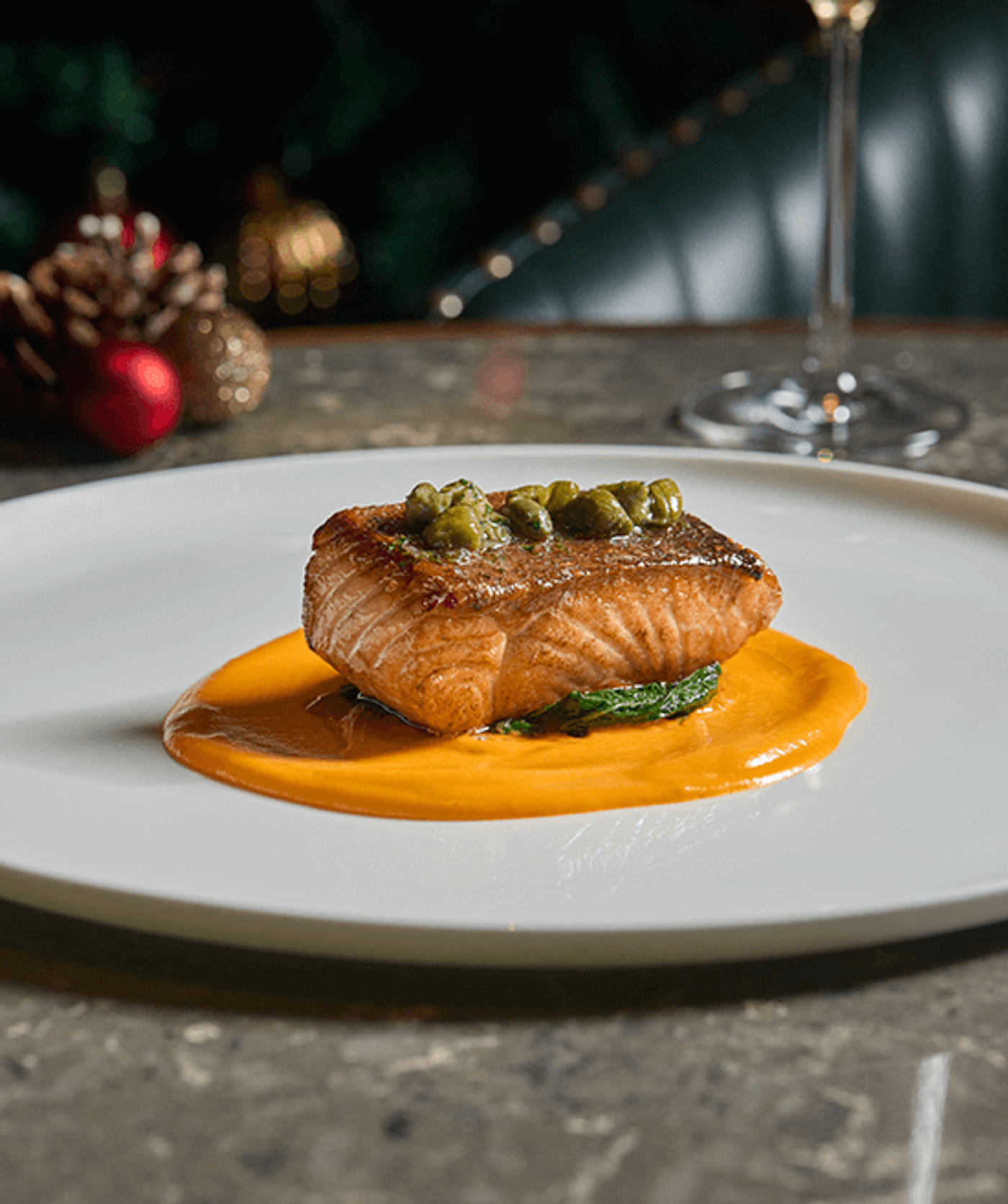 Grilled salmon fillet topped with capers on a sweep of orange carrot puree