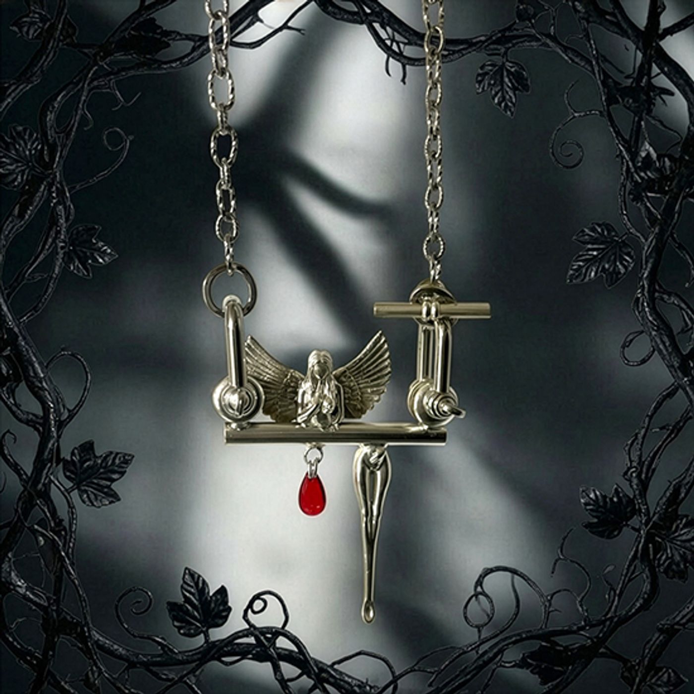 Silver pendant by Michelline Syjuco of a winged figure seated on a bar hung with a red garnet drop, framed by dark vines