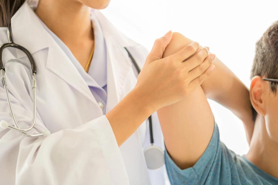 Physician assessing joint mobility and inflammation in a rheumatology outpatient clinic