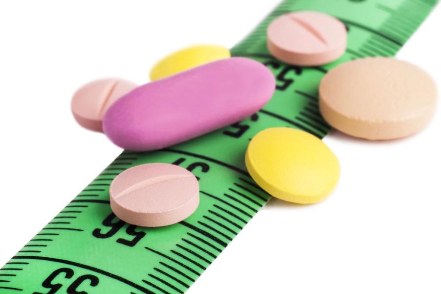 Weight loss pills with measuring tape representing obesity treatment