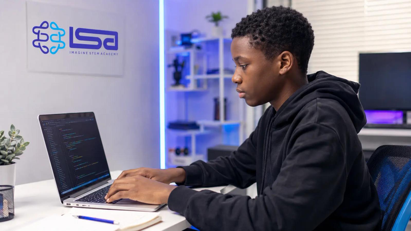 African teenager learning to code on a laptop during an Imagine STEM Academy coding class.