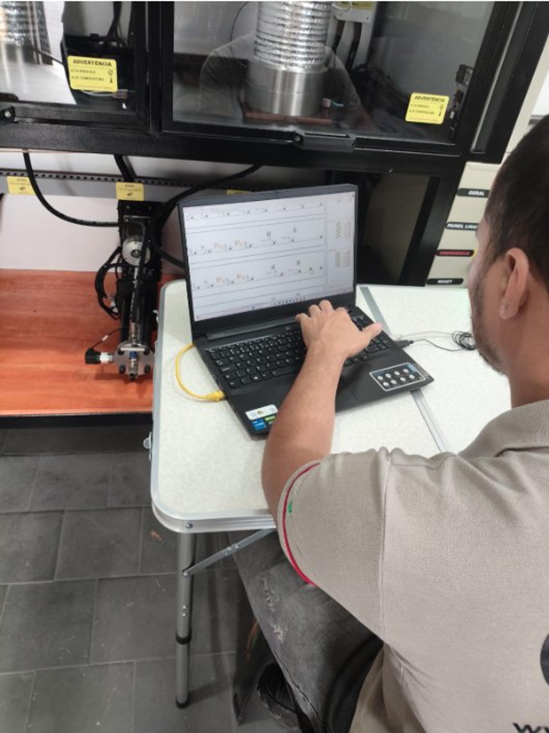Técnico da GRD conduz um ensaio pelo programa, no notebook ao lado da máquina