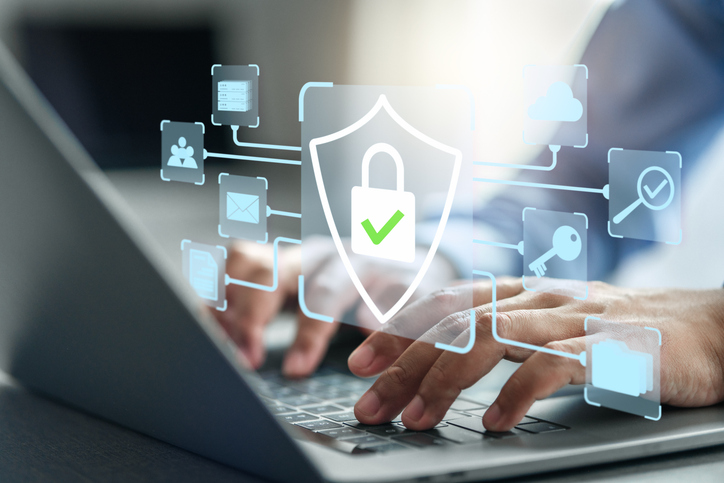 Hands hovering over laptop with cyber icons