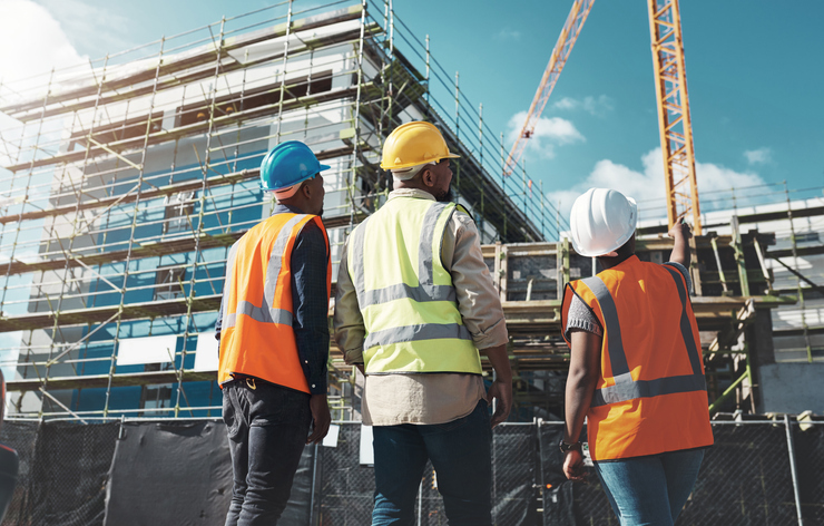 Three trades people looking at construction site