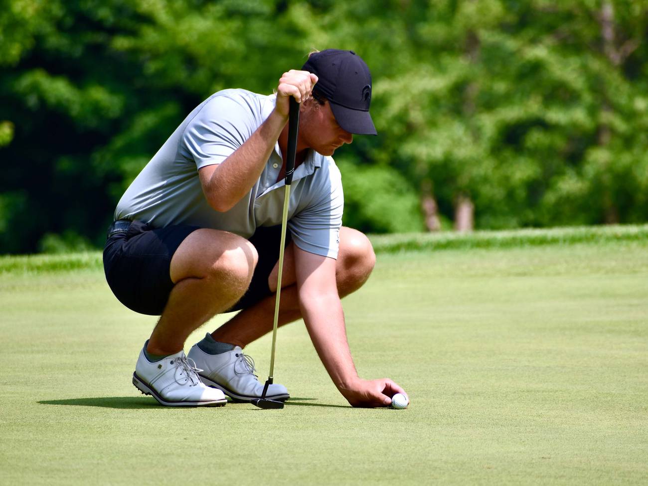 Golfer placing ball on green
