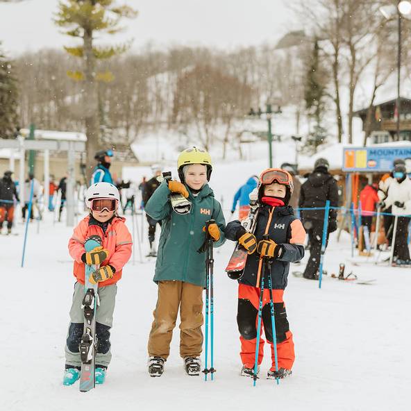 Children in ski gear holding their skis and posing at Boyne Mountain