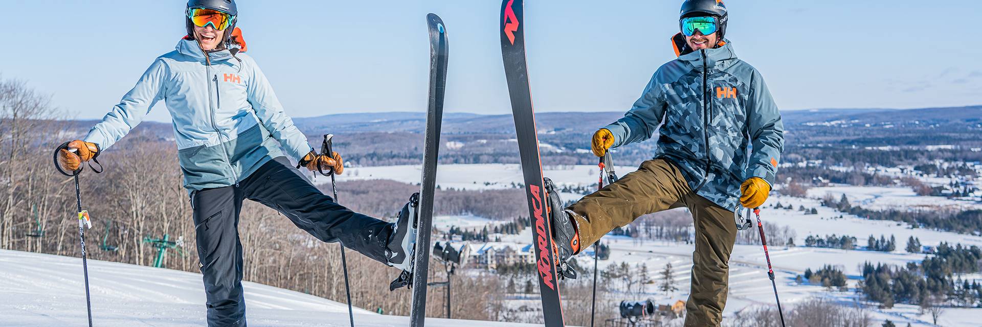 Couple on top of ski hill with skis vertical