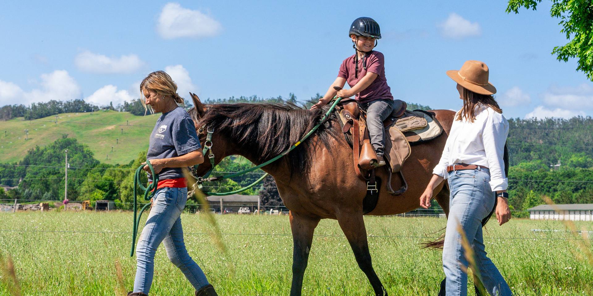 Child riding wrangler-led horse with parent walking alongside