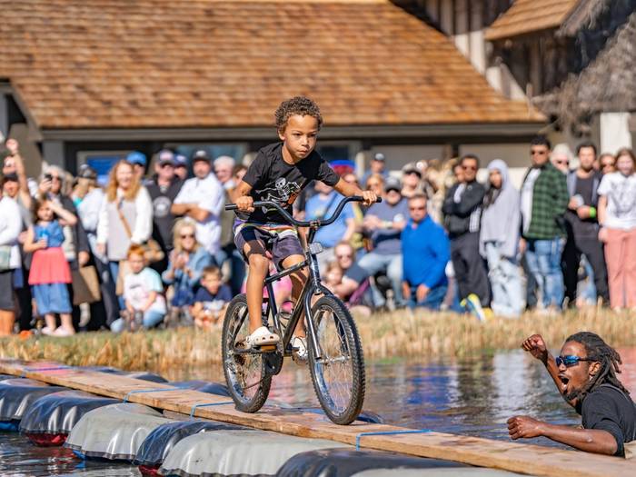 Child biking across pond obstacle