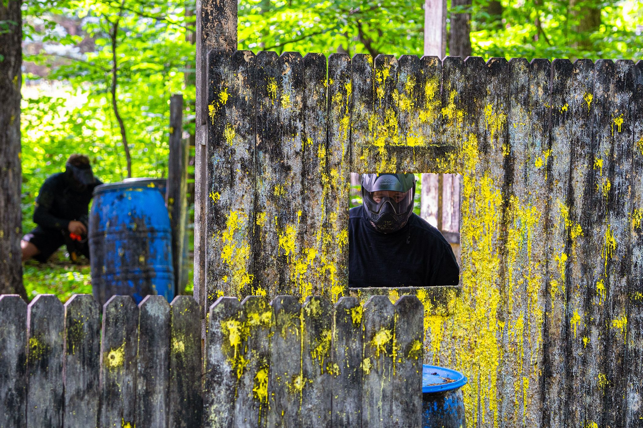 Guy behind paintball fence.