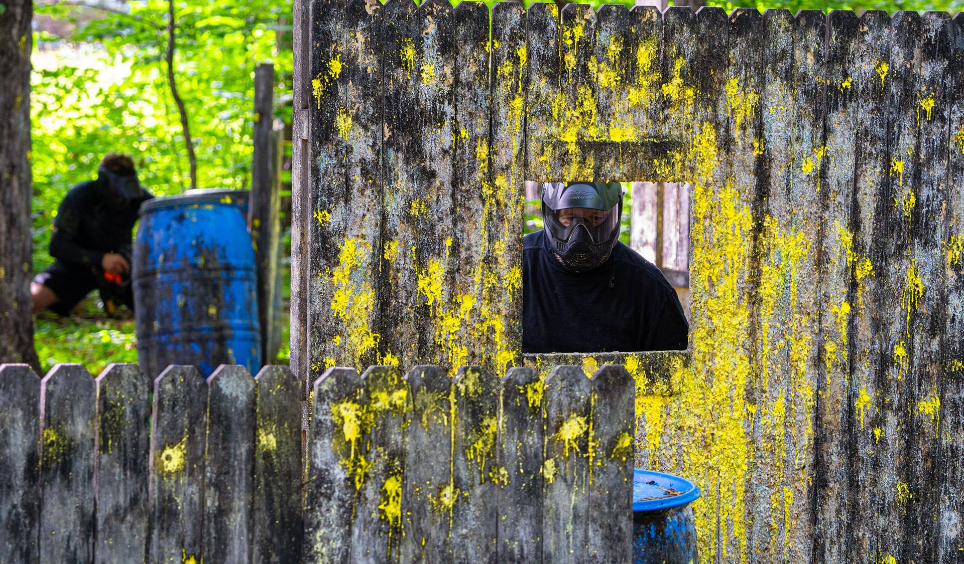 Guy behind paintball fence.