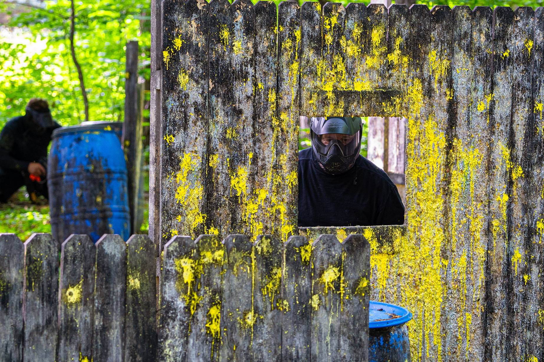 Guy behind paintball fence.