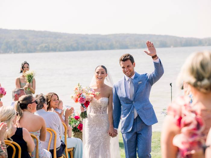 Couple waving after vows walking out down the aisle