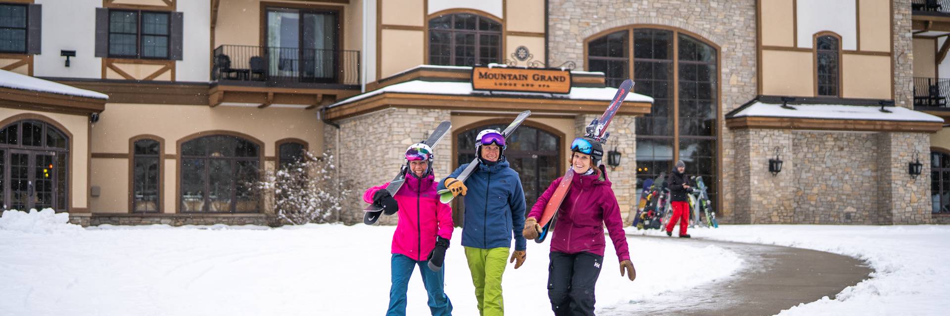 Group walking on sidewalk carrying skis in winter