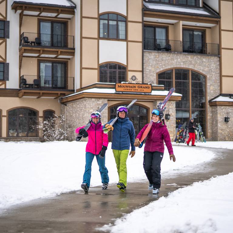 Skiers carrying there skis out of Mountain Grand Lodge and Spa
