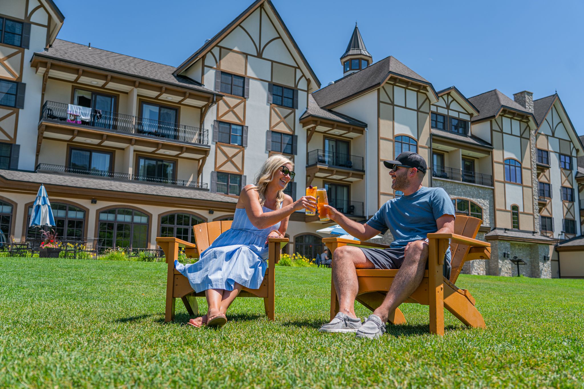 Couple sitting in adirondack chairs in the Mountain Grand Lodge and Spa with drinks