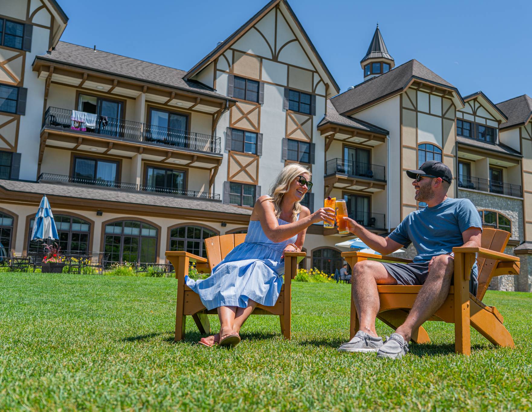 Couple sitting in adirondack chairs in the Mountain Grand Lodge and Spa with drinks