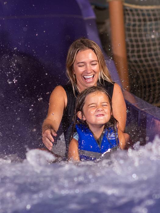 Mom and daughter riding down waterslide