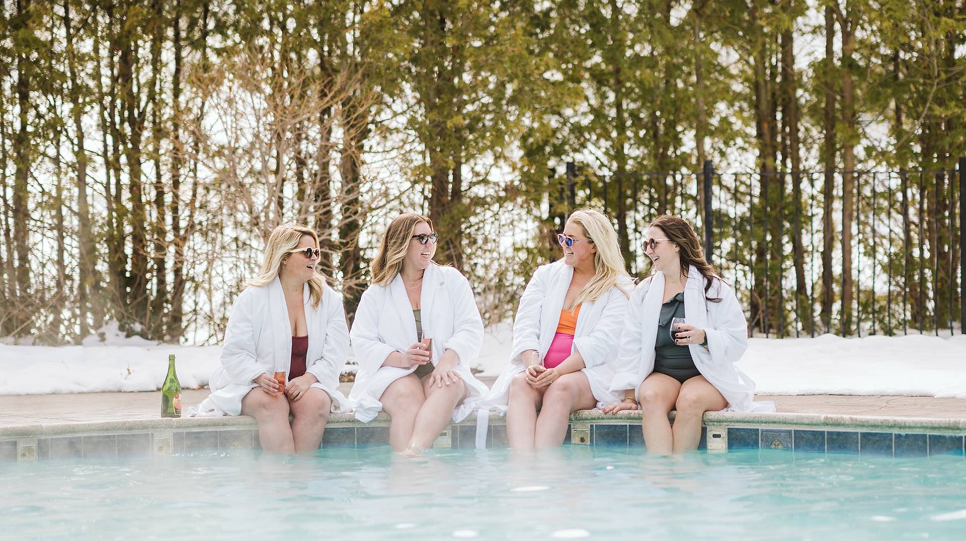 Ladies in robes with feet in the pool