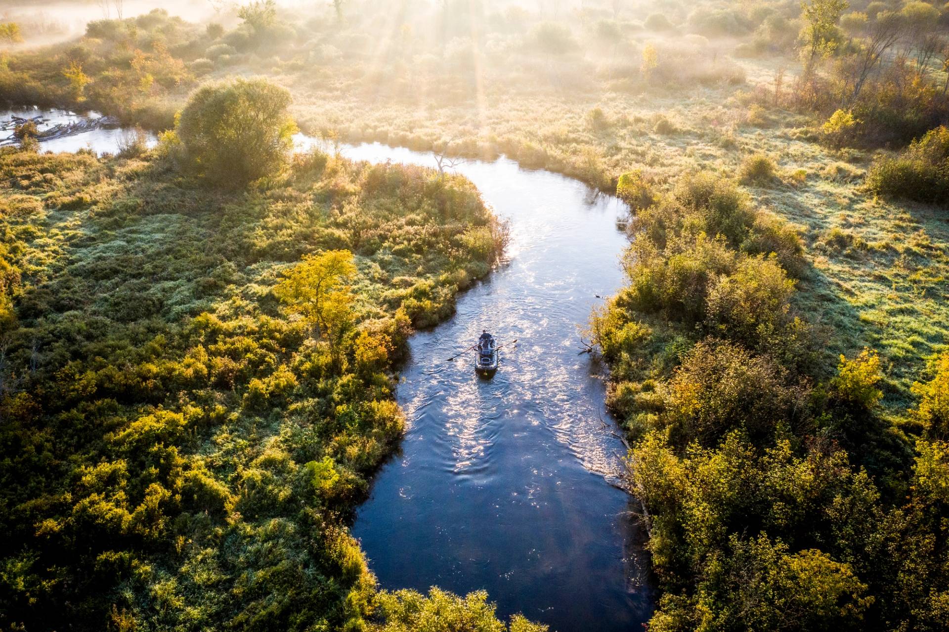 Drone photo of boat floating down the river in morning light