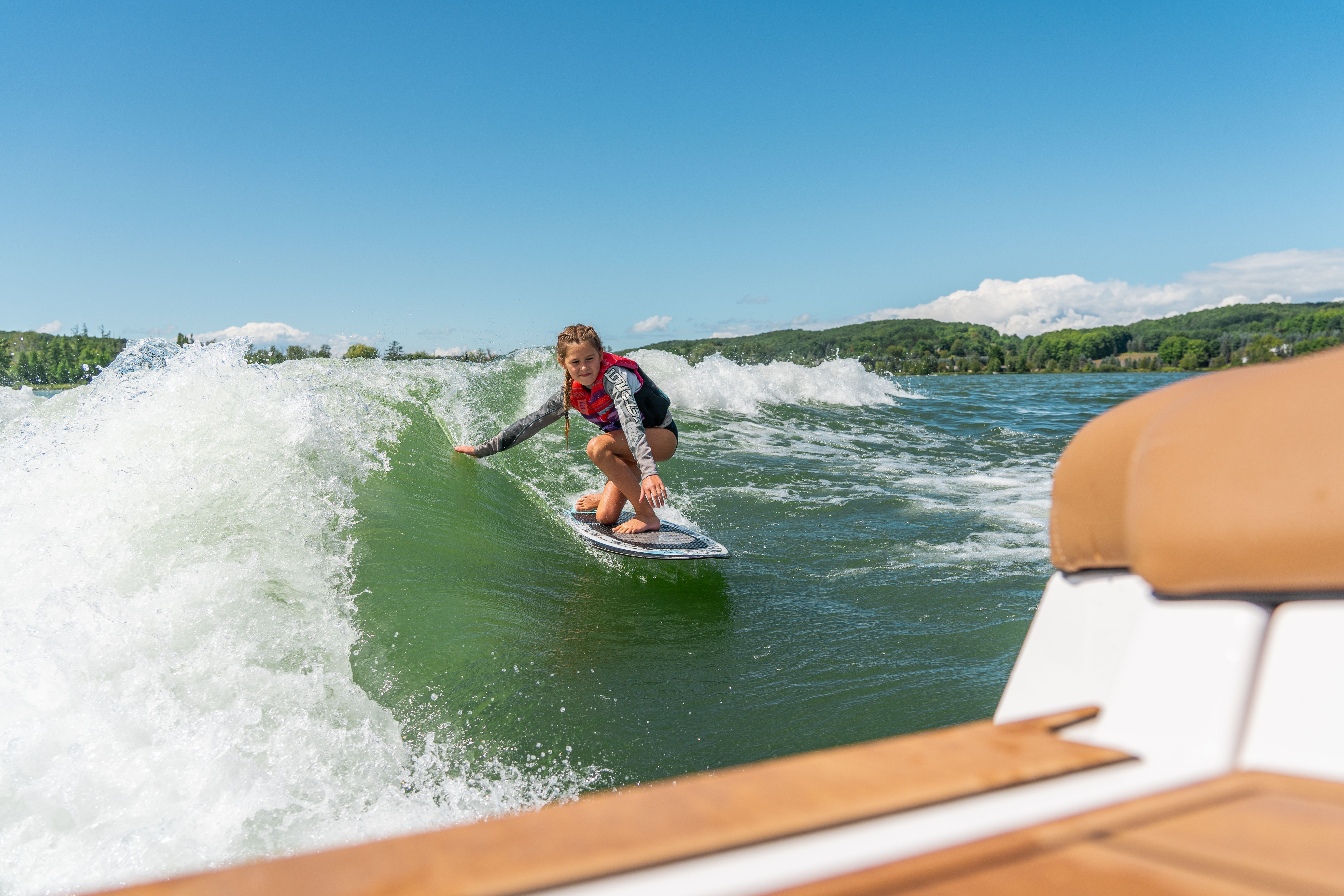 Girl surfing behind wake boat.