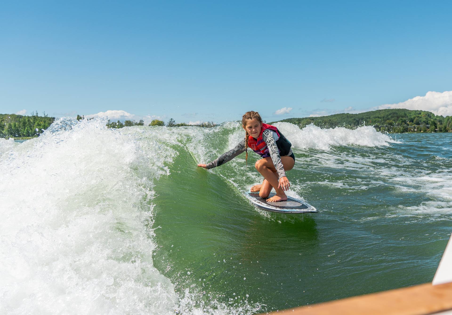 Girl surfing behind wake boat.