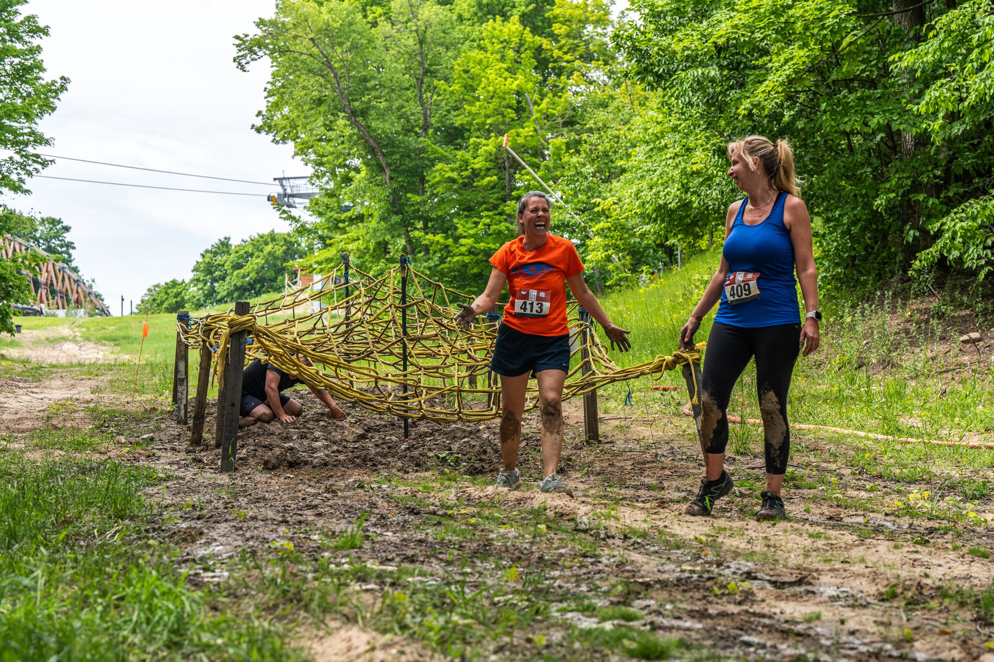Racers standing up and smiling after crawling under rope obstacle