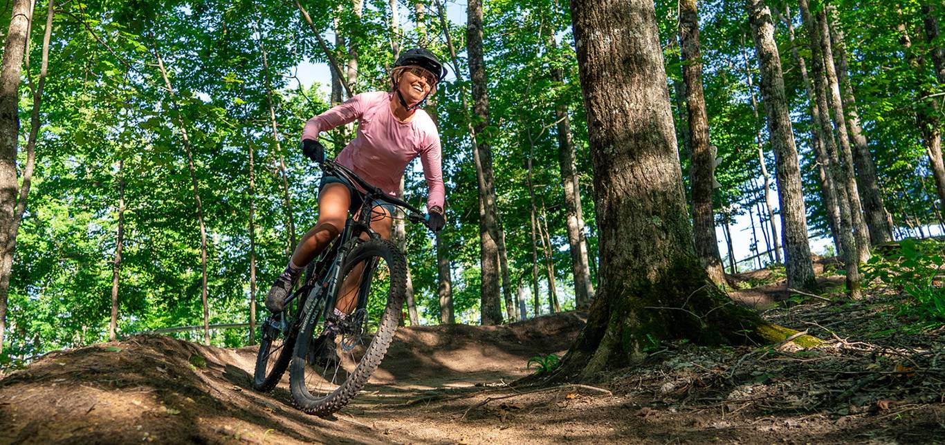 Woman mountain biking through the woods