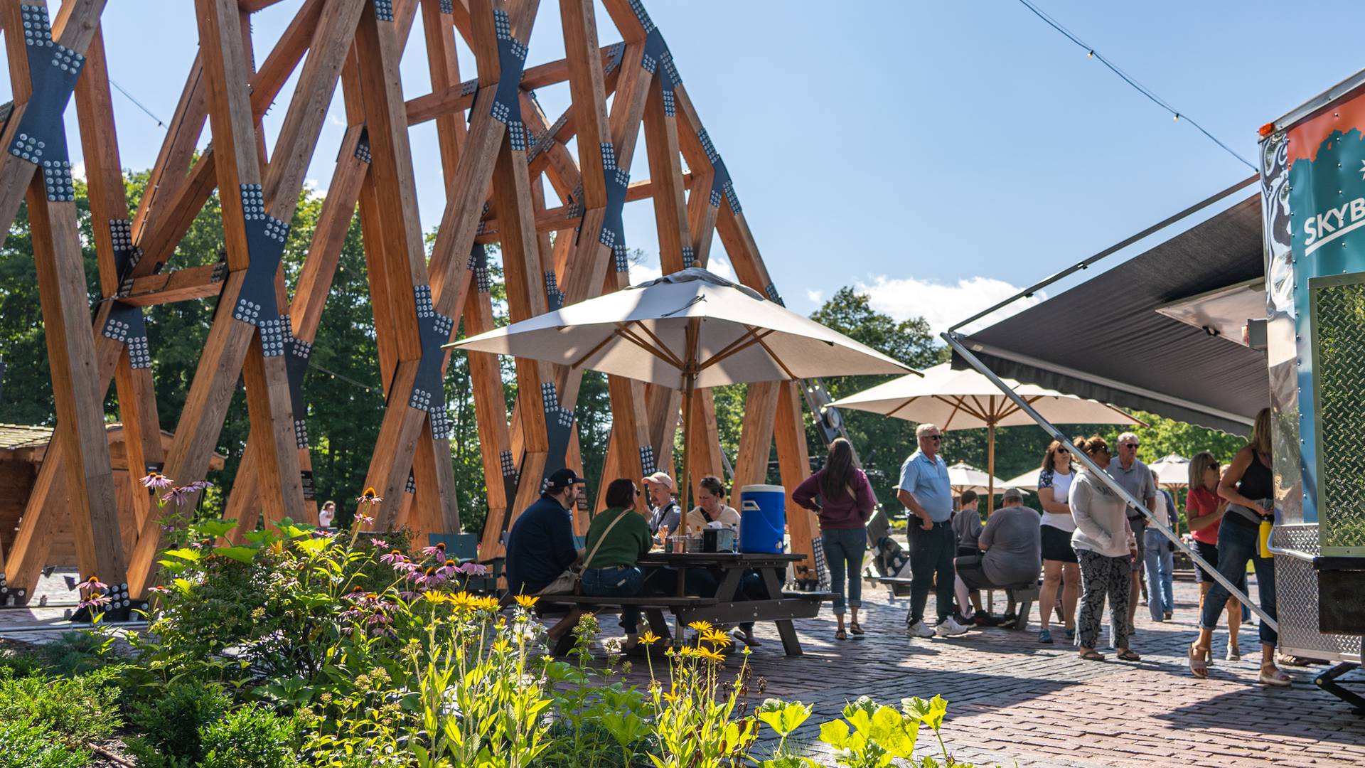 Guests sitting at picnic tables at SkyBridge Michigan food truck