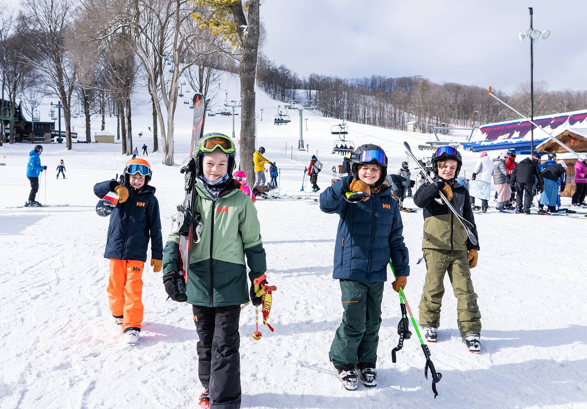 Group of kids carrying skis on the mountain base
