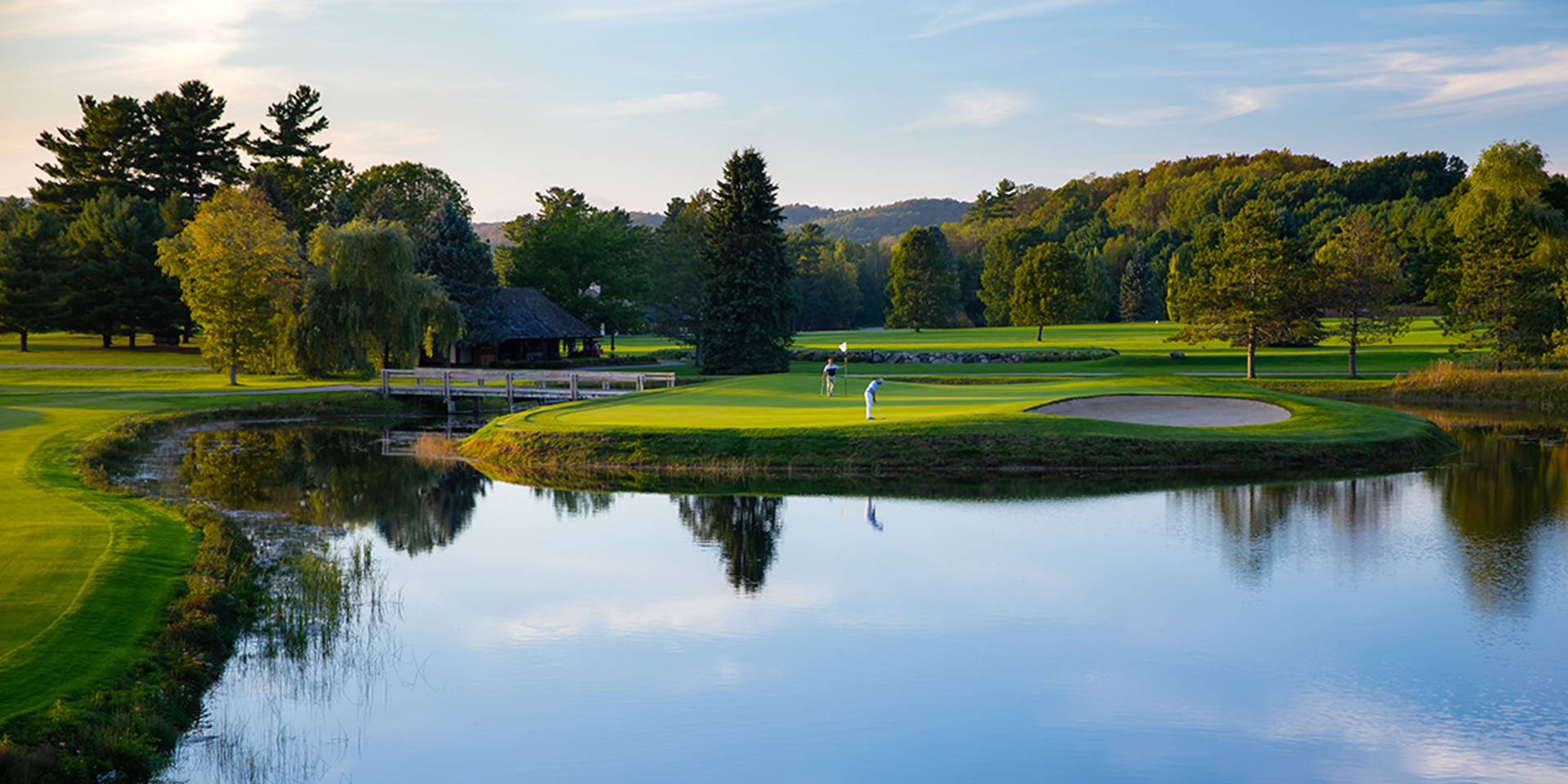 golfers on the green circled by a pond