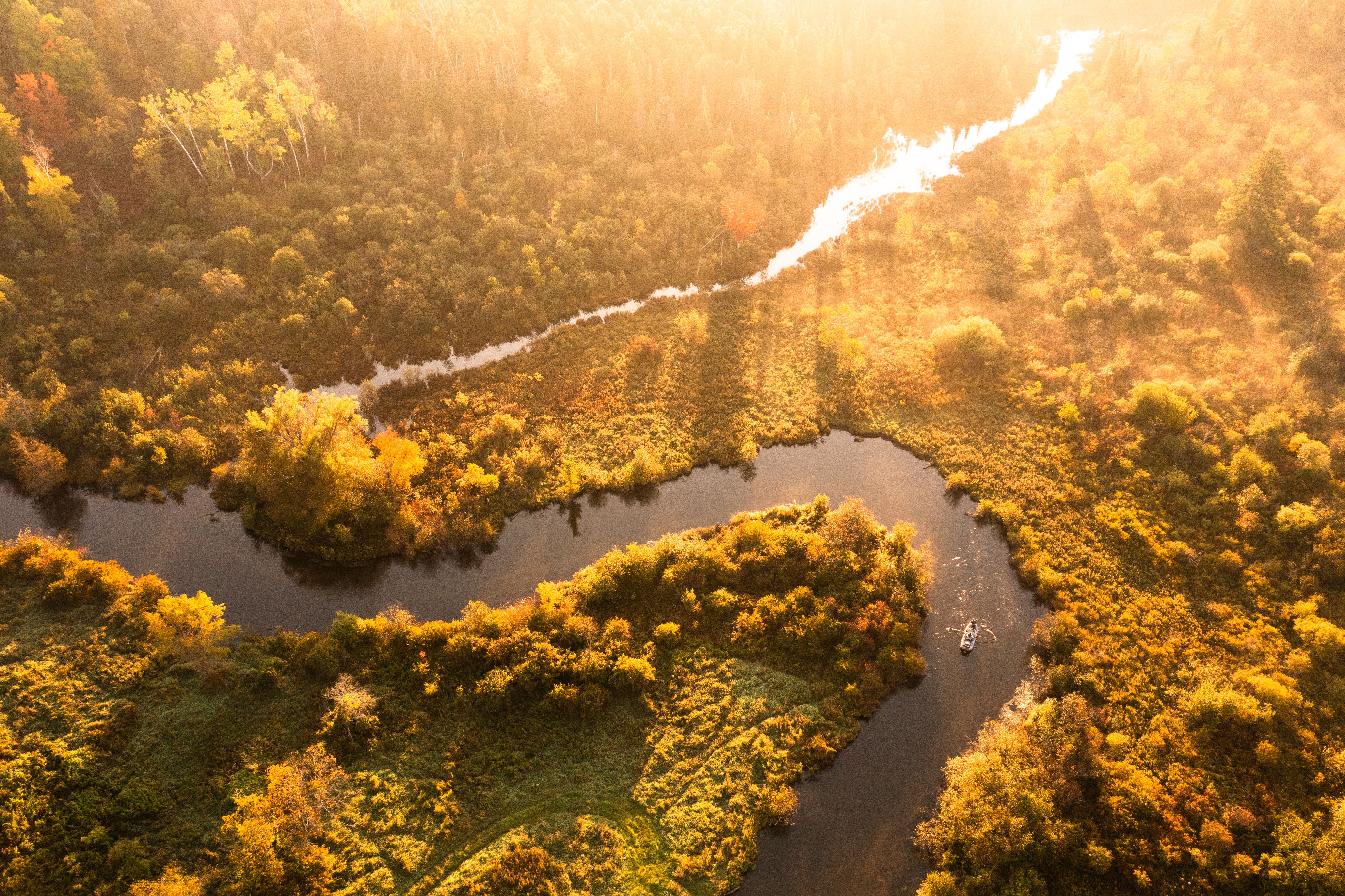 Boat floating down river during golden hour.