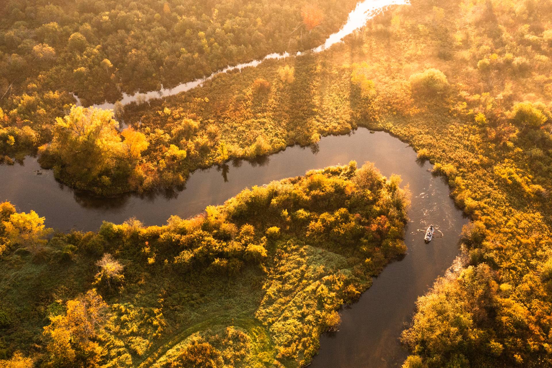 Boat floating down river during golden hour.