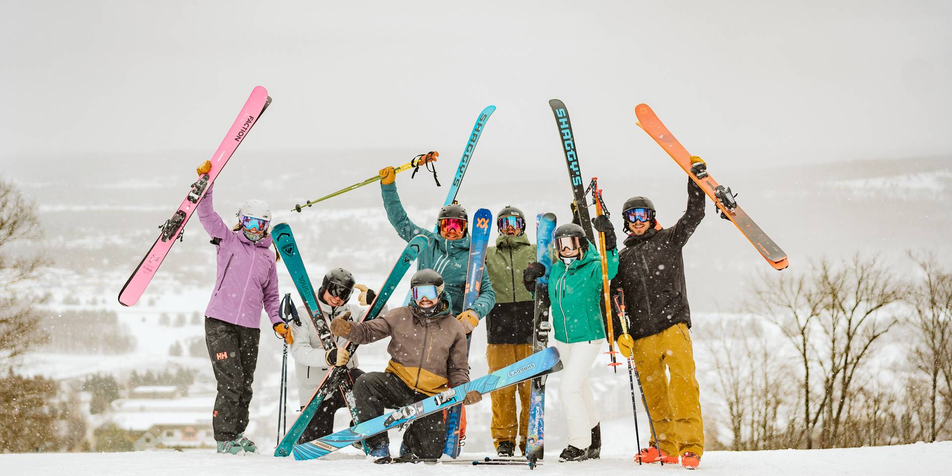 large group of skiiers holding up skiis
