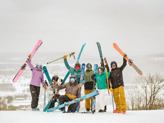 large group of skiers holding up skiis