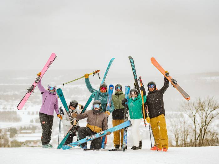 large group of skiers holding up skiis