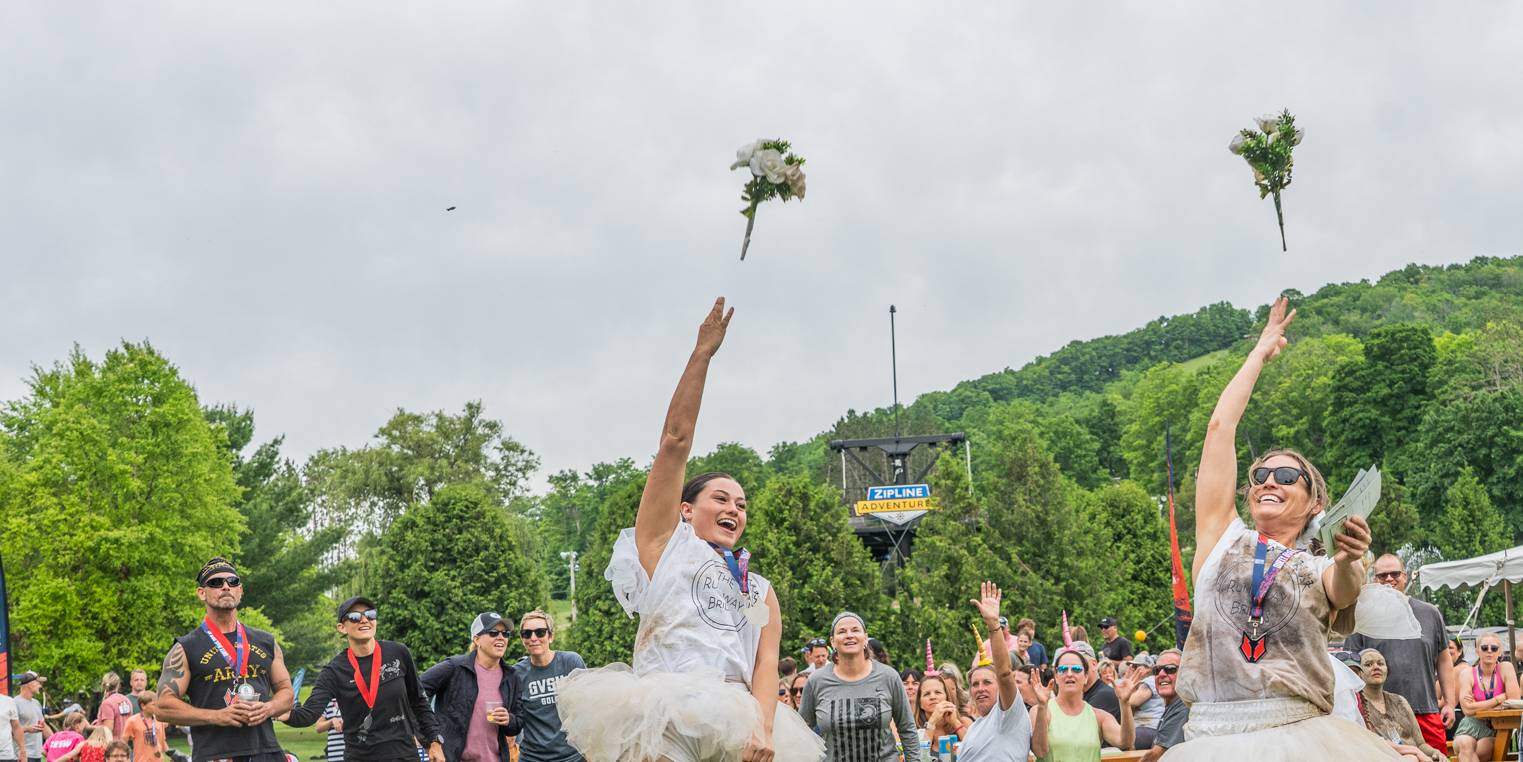 Racers dressed as brides throw flowers into the crowd