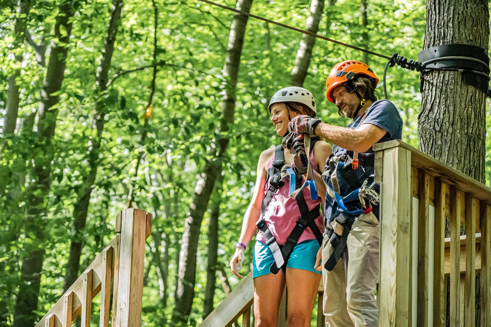 Zipline instructor with girl getting ready to zipline.